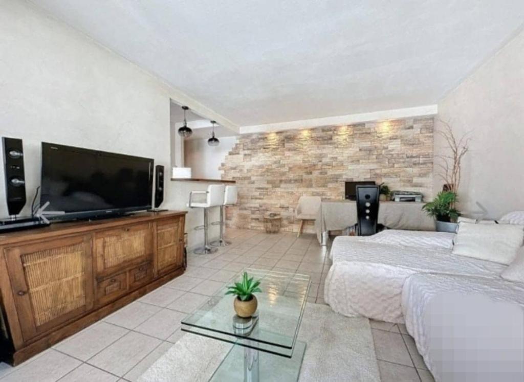 Il comprend un salon doté d'un canapé blanc et d'une télévision à écran plat. dans l'établissement Beau T2 à 200m de la mer et proches toutes commodités, à Antibes