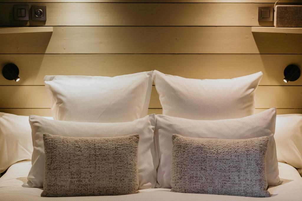 a group of pillows on a bed with white pillows at Hôtel Restaurant La Ferme de Cupelin in Saint-Gervais-les-Bains