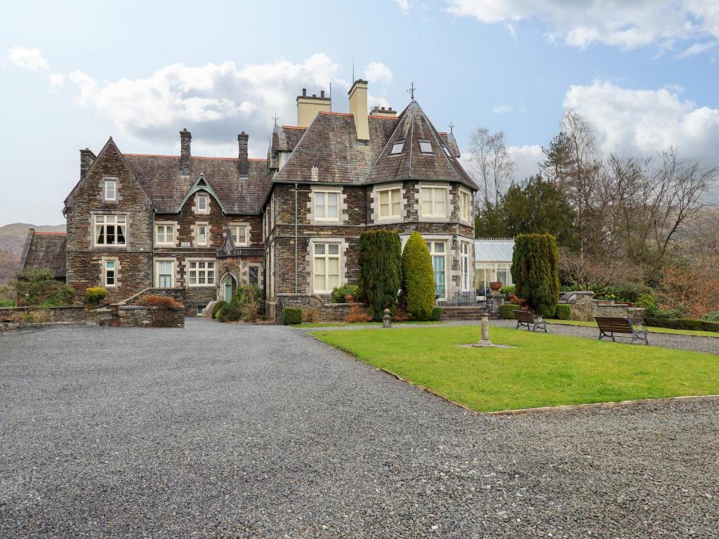 una casa vieja con un patio de hierba delante de ella en The Lookout, en Ambleside