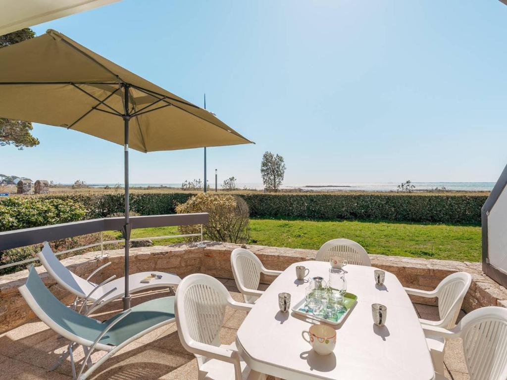 une table et des chaises blanches avec un parasol dans l'établissement Appartement 4 pièces à Carnac - Vue mer, terrasse, parking, accepte animaux - FR-1-477-72, à Carnac