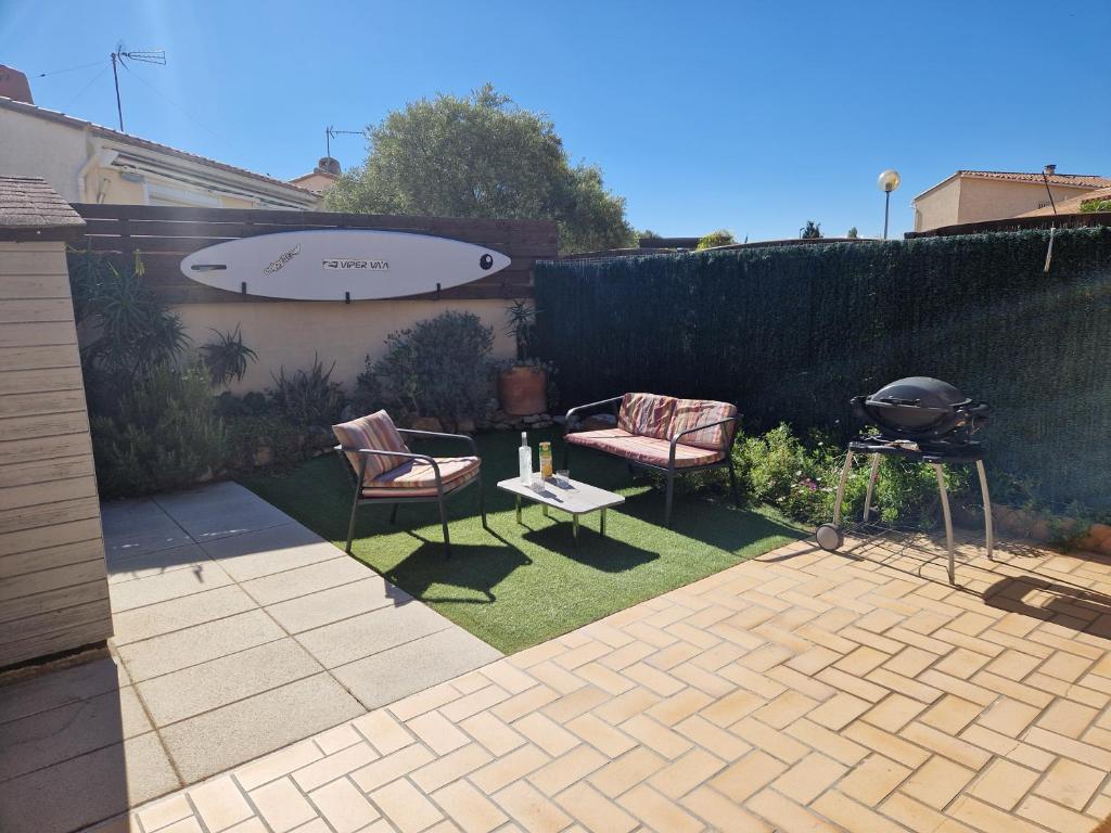 une arrière-cour avec un grill, 2 chaises et un barbecue dans l'établissement maison à louer, à Saint Cyprien Plage