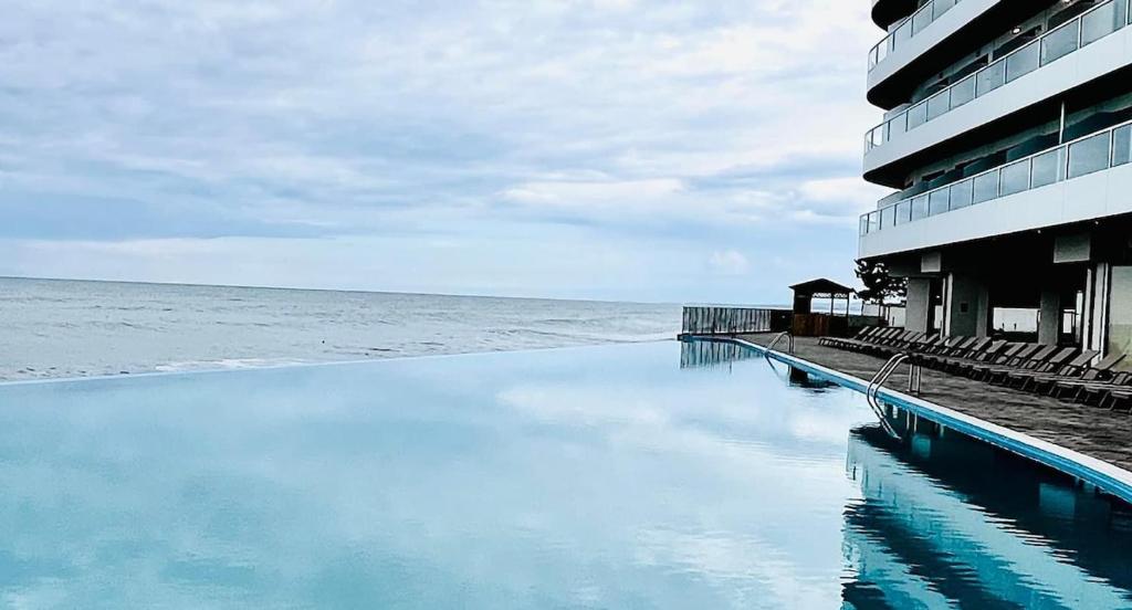 a swimming pool next to a building next to the ocean at Bamboo Beach Tsikhisdziri Seaview Flat 839 in Tsikhisdziri