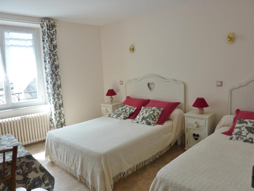 1 dormitorio con 2 camas con almohadas rojas y ventana en Villa Lutetia, en Le Mont-Dore