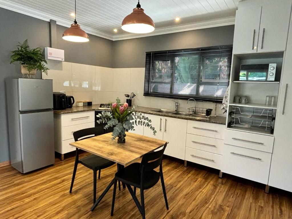 a kitchen with a table with chairs and a refrigerator at Prospect Cottage B in Gqeberha
