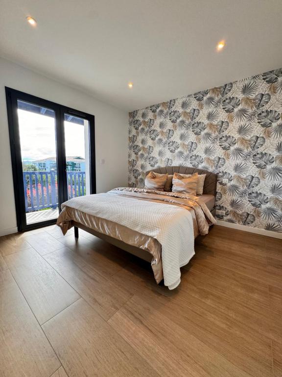 ein Schlafzimmer mit einem großen Bett und einem großen Fenster in der Unterkunft Luxueuse Villa contemporaine avec piscine à deux pas des plages de Biarritz in Bidart