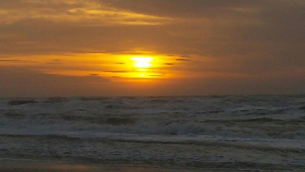 einen Sonnenuntergang am Strand mit dem Meer in der Unterkunft Vredehof in Sint Maartensbrug