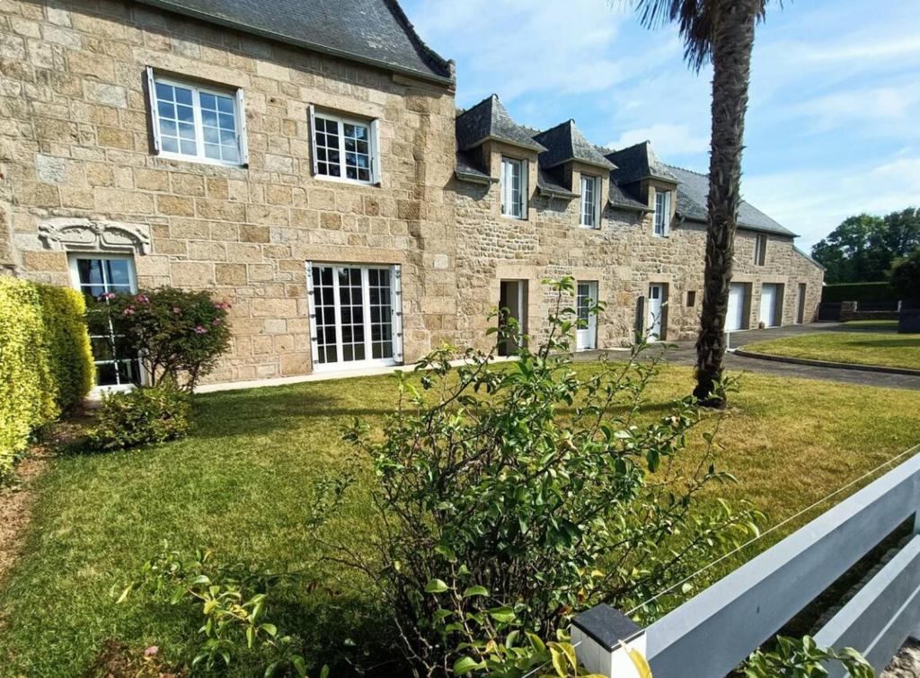 - un grand bâtiment en pierre avec un palmier devant dans l'établissement La trouvaille des retrouvailles, à Saint-Marc-le-Blanc