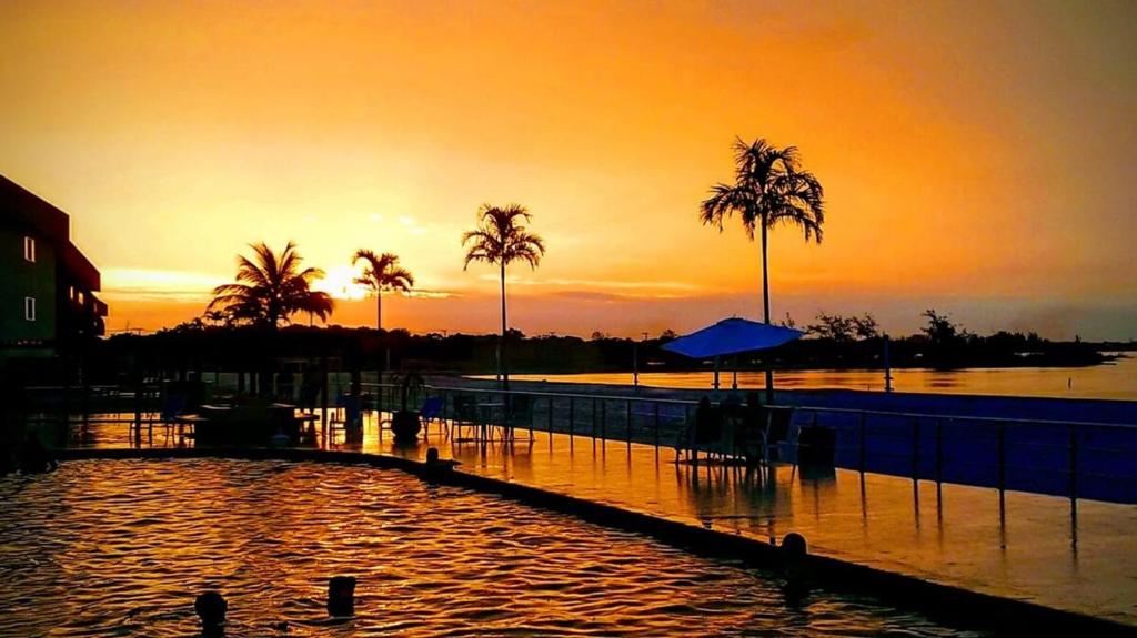 a sunset over a body of water with palm trees at Golden Lake Experiência Inesquecível 6 apto 301 in Arraial do Cabo