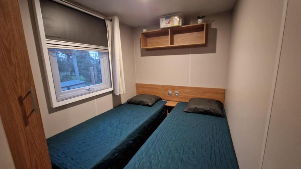 deux lits dans une petite pièce avec une fenêtre dans l'établissement Mobihome les sables du midi, à Valras-Plage