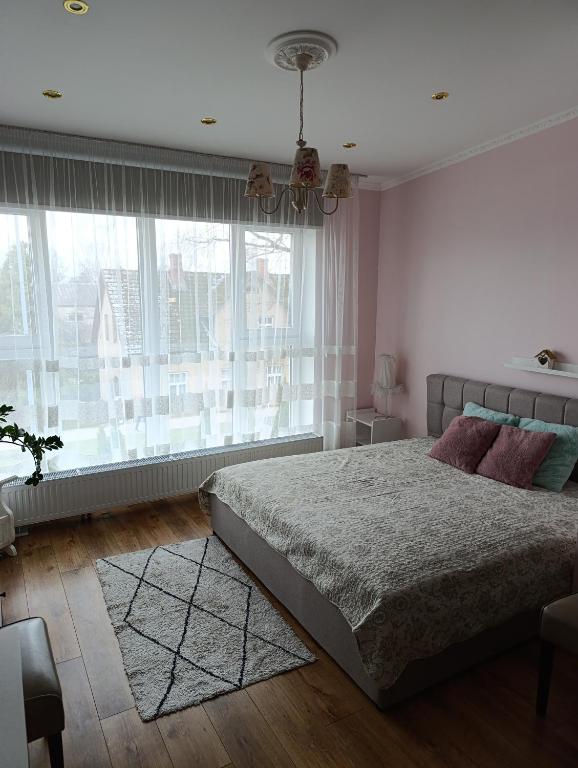 a bedroom with a bed and a large window at Liepu ielas rezidence in Valmiera