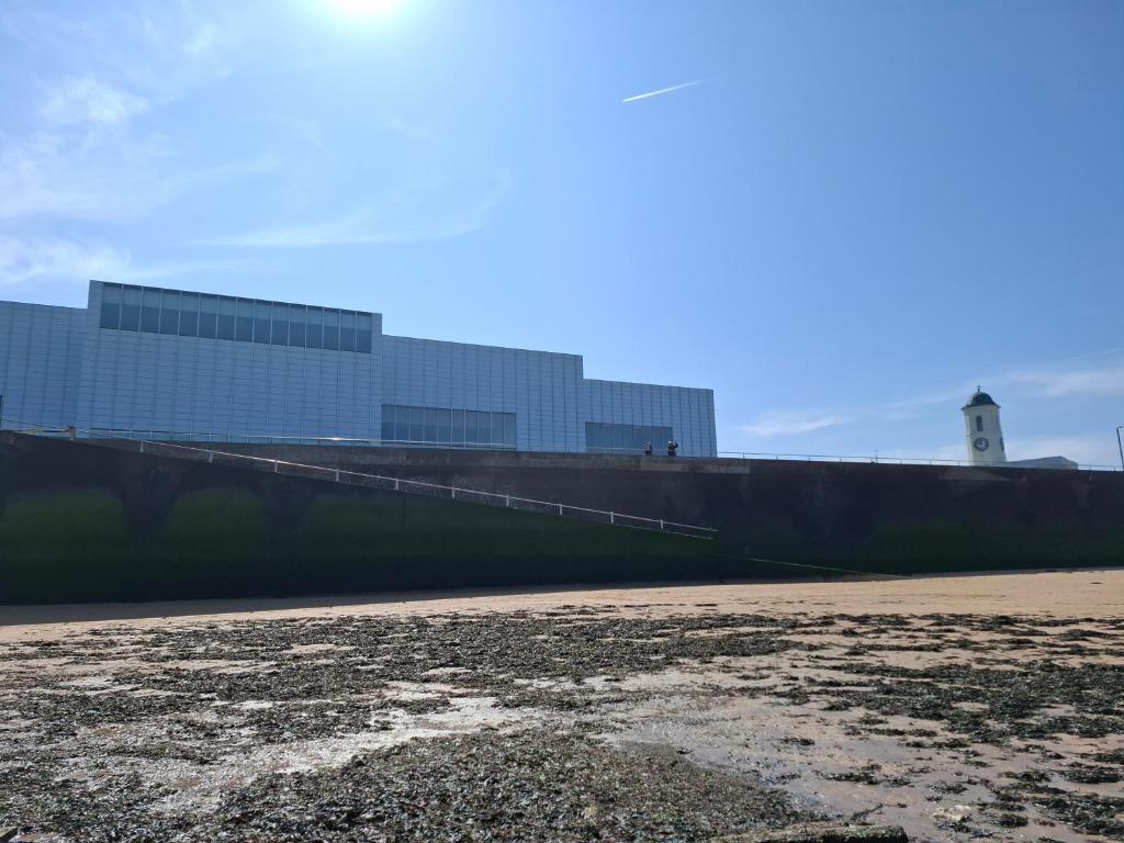 a wall with a building in the background with a beach at Westbrook Lodge Guest House in Margate