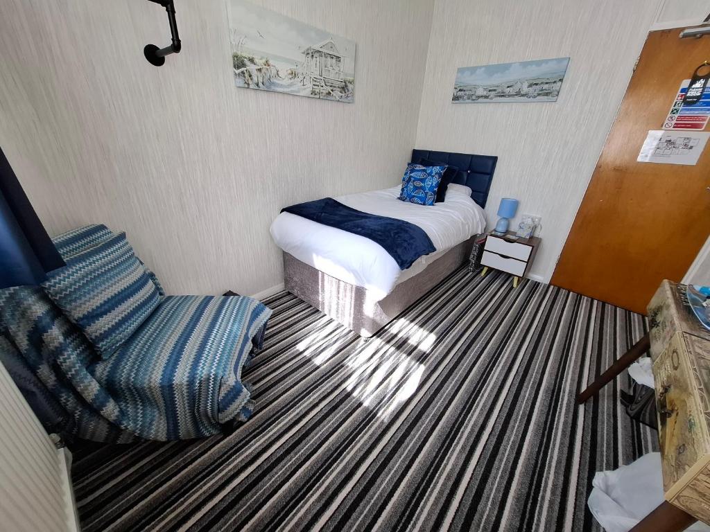 a small bedroom with a bed and a chair at Westbrook Lodge Guest House in Margate