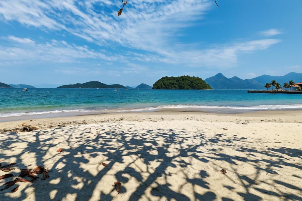 una sombra de una persona volando una cometa en una playa en Apartamentos, 3 Praias, condomínio de Luxo, Piscinas, en Angra dos Reis