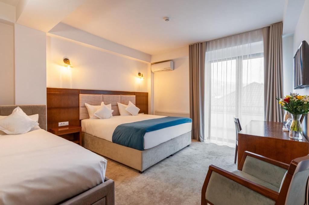 een hotelkamer met twee bedden en een bureau bij Hotel Buchenland in Gura Humorului