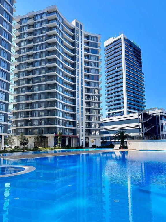 a large swimming pool in front of tall buildings at Luxury Suites White Sails in Batumi