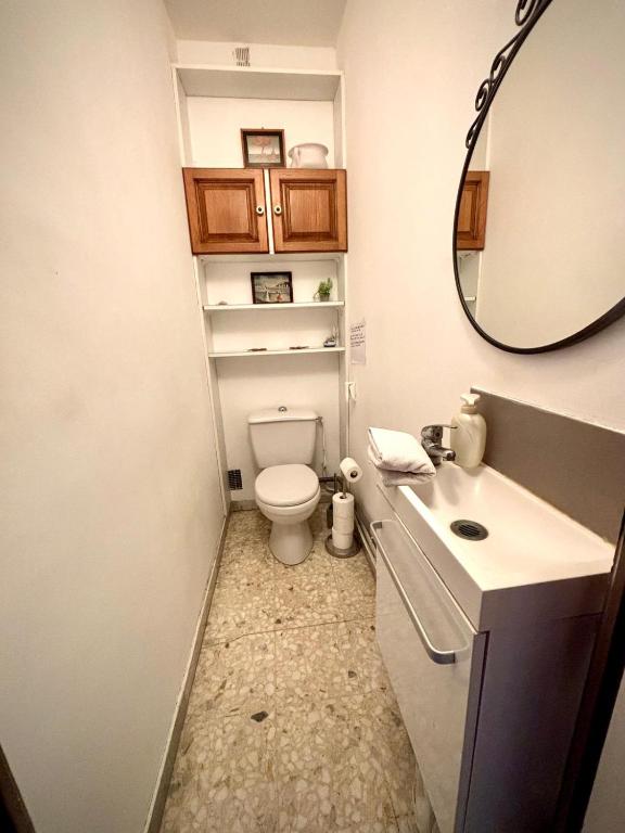 W łazience znajduje się toaleta, umywalka i lustro. w obiekcie Évasion aux Portes de Cannes 100m2 Lumineux 2 Chambres Terrasse et Commerces w mieście Le Cannet