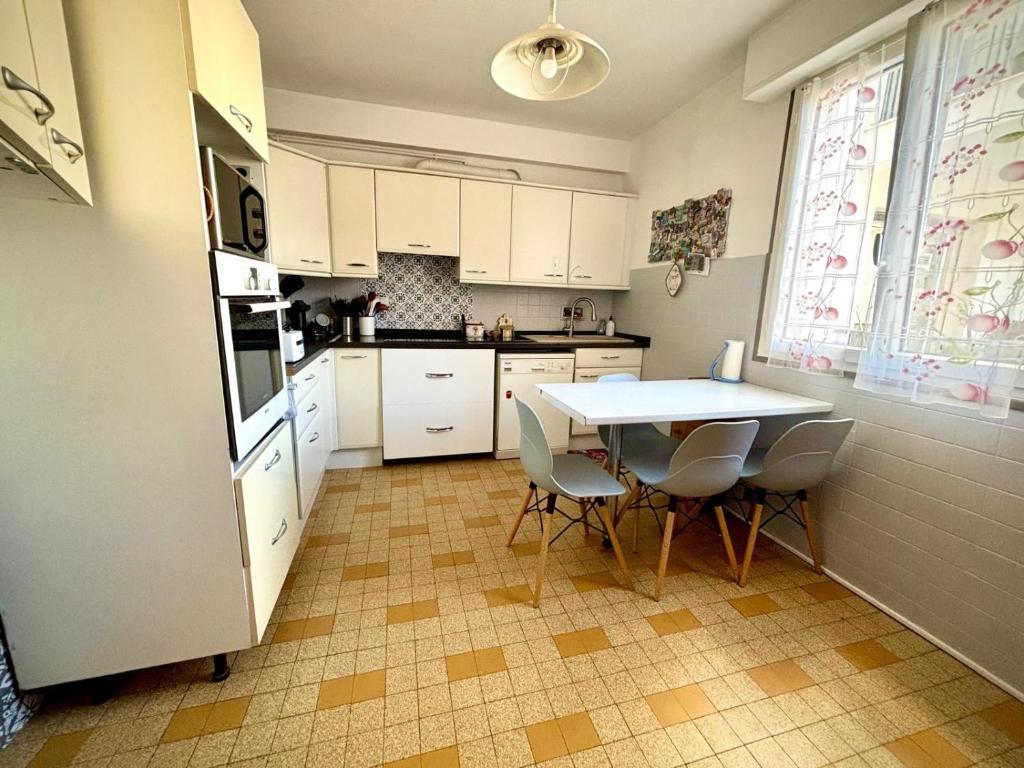kuchnia z białymi szafkami, stołem i krzesłami w obiekcie Évasion aux Portes de Cannes 100m2 Lumineux 2 Chambres Terrasse et Commerces w mieście Le Cannet