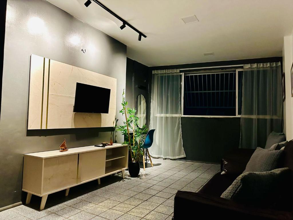een woonkamer met een bank en een flatscreen-tv bij Vista mar, piscina, na praia do futuro, com Ar condicionado e Wi-Fi in Fortaleza