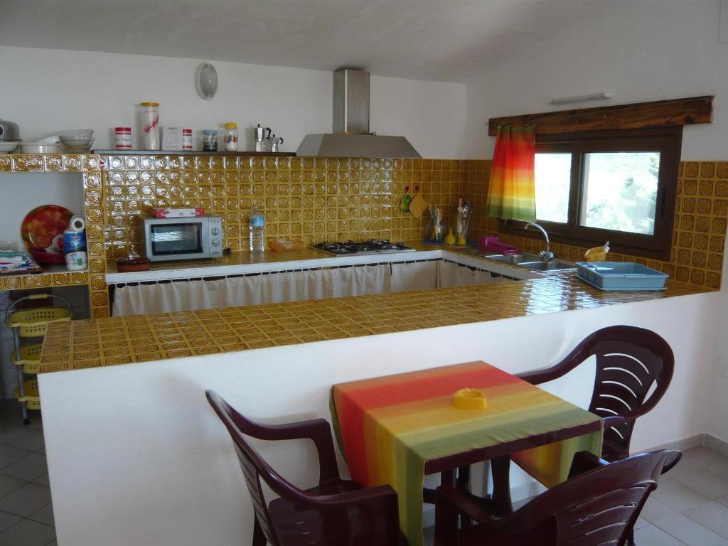 ラ・マッダレーナにあるCasa Vacanze Abbatoggiaのキッチン(カウンター、レインボースツール付きテーブル付)