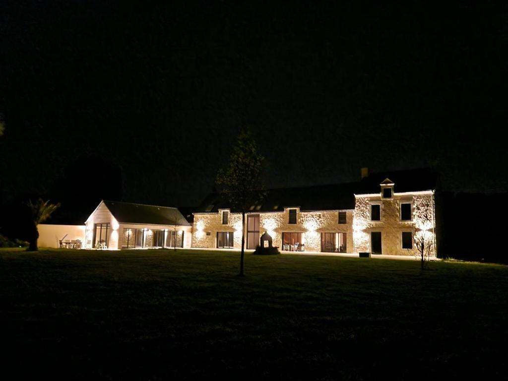 un grand bâtiment avec des lumières allumées la nuit dans l'établissement Cottage du Golfe - 2 logements - 18 personnes, à Plescop