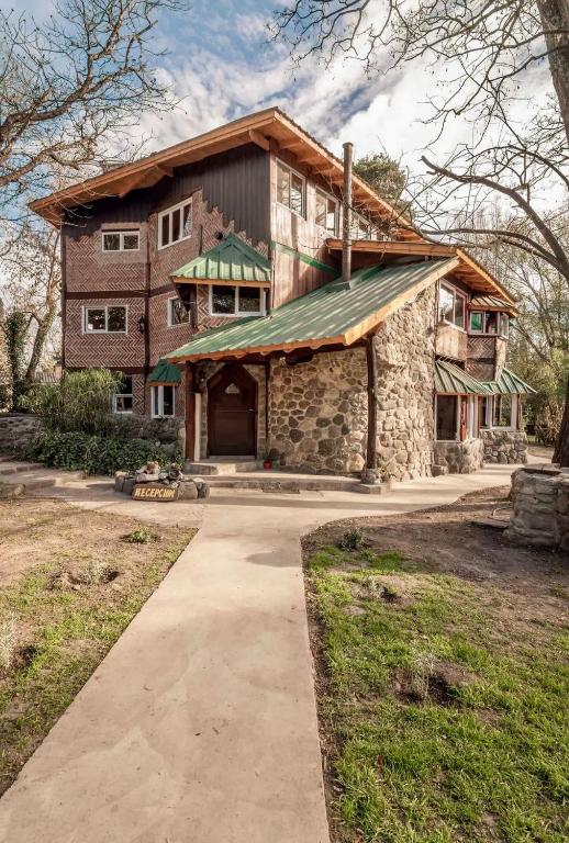 a large stone house with a green roof at HOSTEL CASA C Alojamiento, Coworking y Centro Cultural in Villa General Belgrano