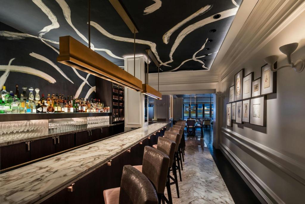 a bar in a restaurant with a long counter and chairs at The Ritz-Carlton New York, Central Park in New York