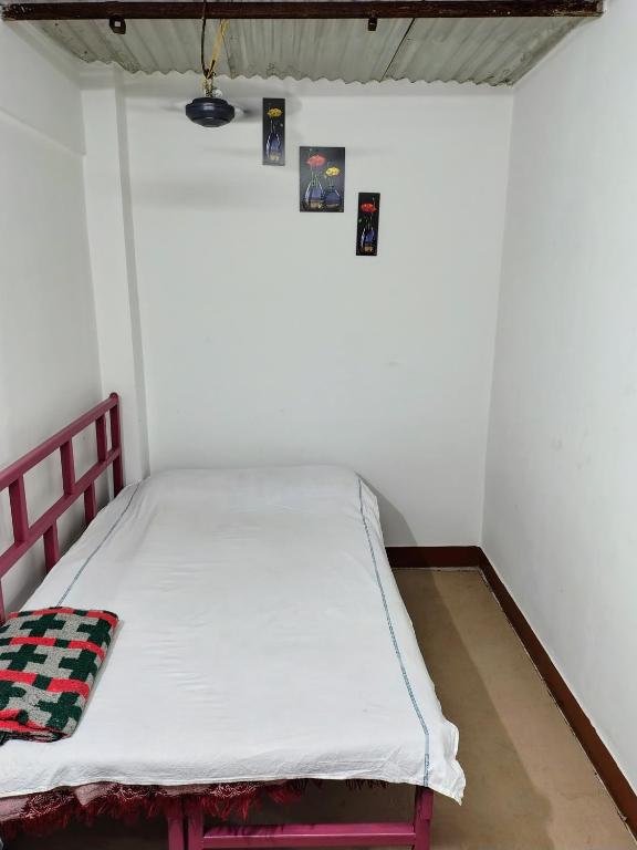 a bed in a room with a white wall at Annada Homestay in Rānchī