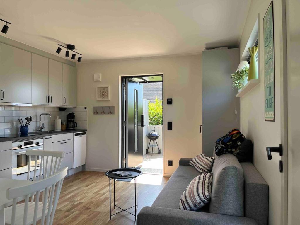 a living room with a couch and a kitchen at Stuga Varberg Södranäs in Varberg