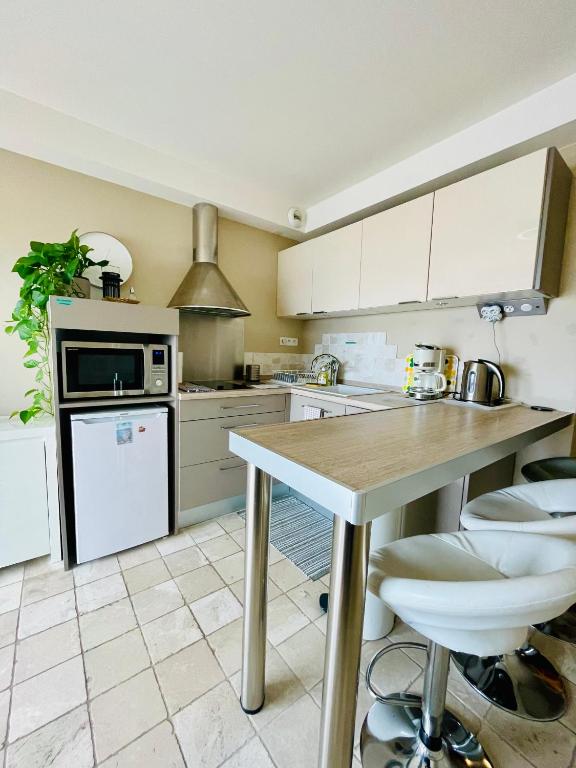 kuchnia z białymi szafkami i stołem z stołkami w obiekcie Superbe appartement en bord de mer, près du centre et des plages w Mentonie