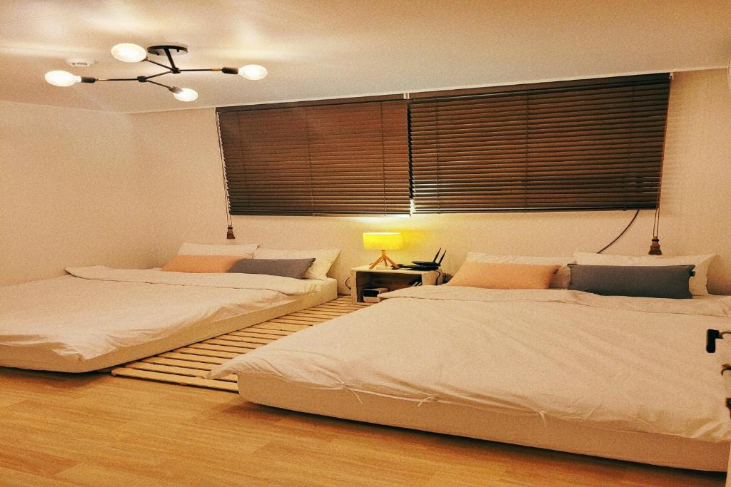 a bedroom with two beds and a window at Hongdae 3mins, Q House in Seoul