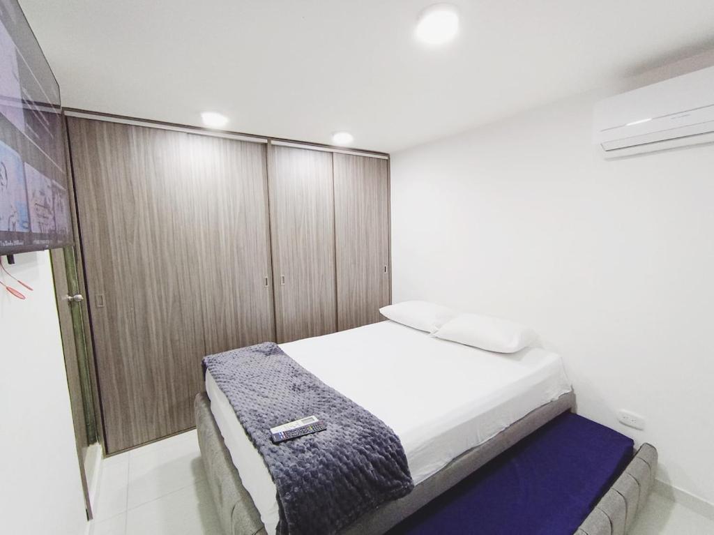 a bedroom with a white bed and wooden cabinets at Apto zona norte a 20 min del buena vista in Barranquilla