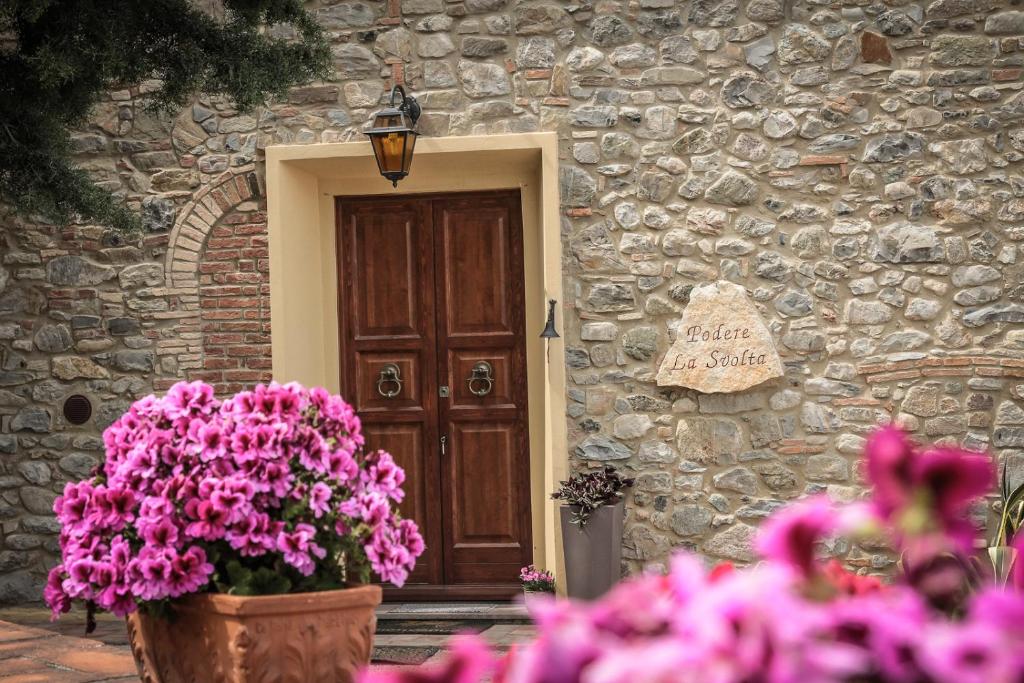 a door of a stone building with flowers in front of it at Podere "la svolta" in Chianni