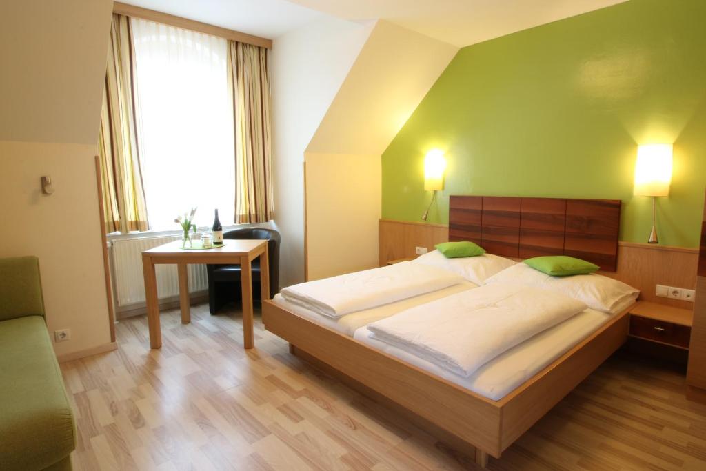 1 dormitorio con 1 cama grande y pared verde en Pension Joseph Haydn, en Podersdorf am See