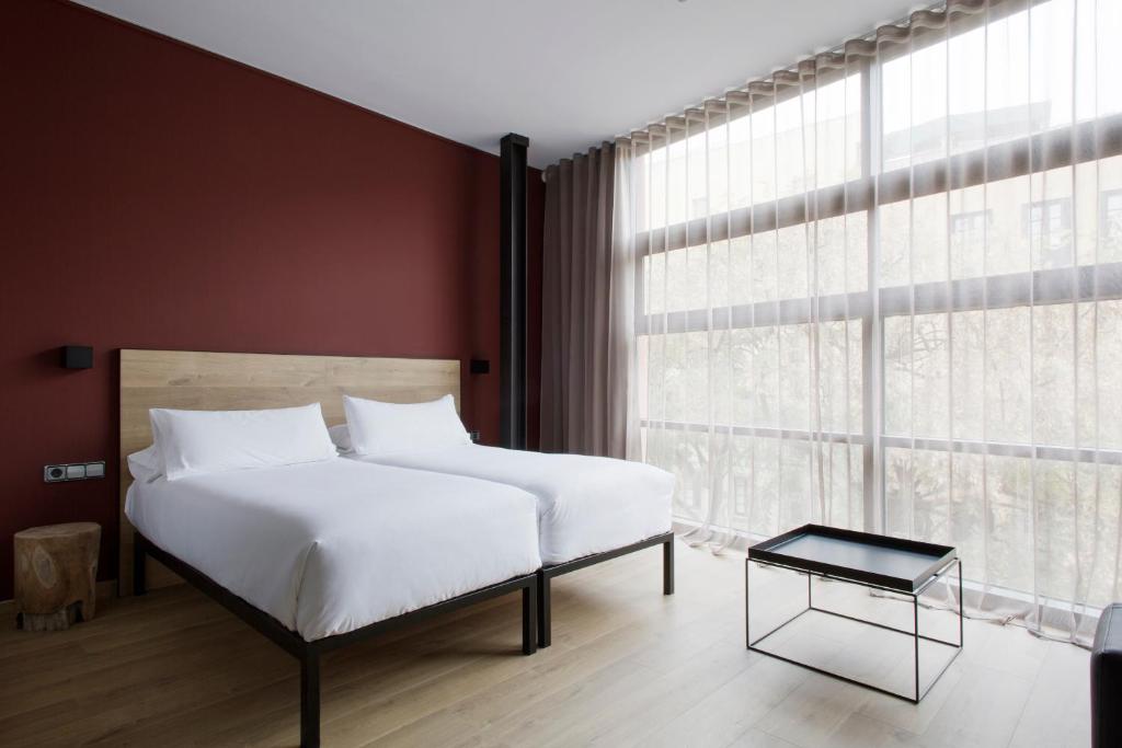 a bedroom with a white bed and a large window at Aparthotel Allada 3* in Barcelona