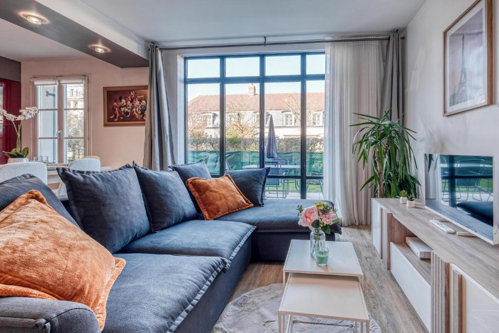 un salon avec un canapé bleu et une grande fenêtre dans l'établissement T3 Disneyland et gare a pied LE DUPLEX 6 ou 7 personnes, à Serris