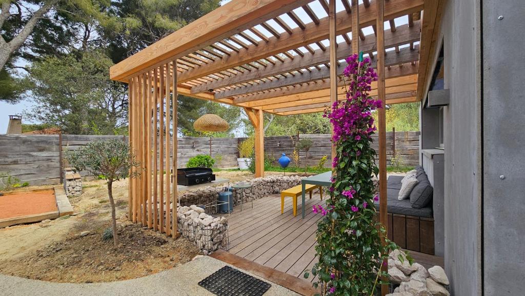 une pergola en bois avec une table et des fleurs violettes dans l'établissement La Maison Bleue, à Saint-Mitre-les-Remparts