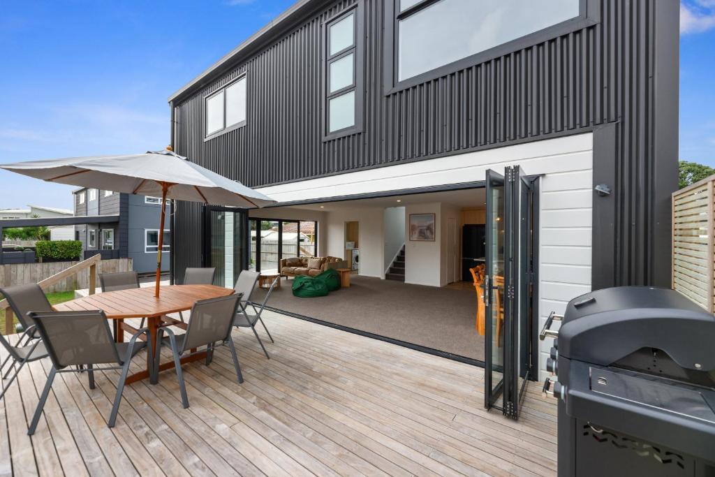 a house with a deck with a table and a grill at Edinburgh Escape - Waihi Beach Holiday Home in Waihi Beach