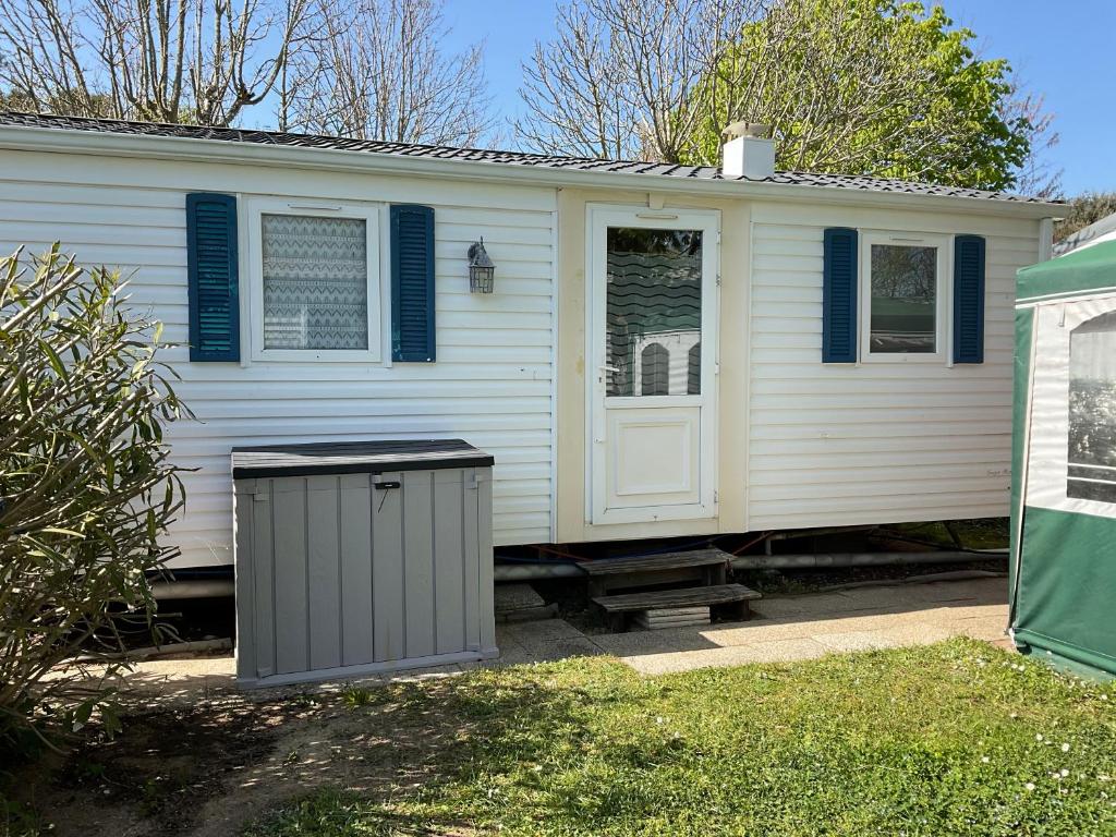 une maison blanche avec une poubelle devant elle dans l'établissement Mobilhome Île d Oléron Camping Les Tamaris, à Saint-Pierre-dʼOléron