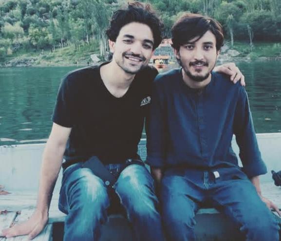 two men sitting on a boat in the water at SK RESORTs in Skardu
