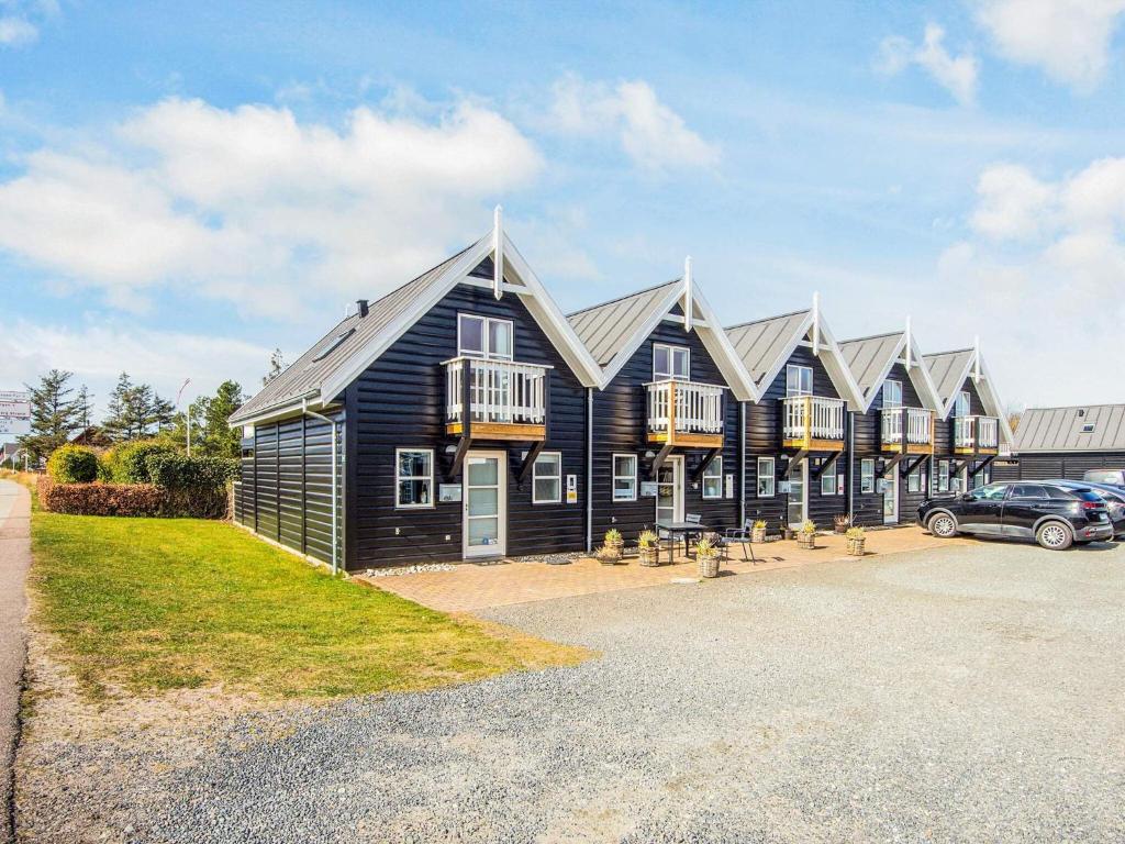 a black house with a car parked in front of it at 4 person holiday home in Blåvand in Blåvand