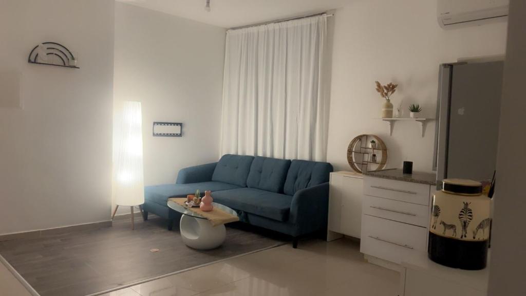 a living room with a blue couch and a table at פנטהאוז 2 חדרים עם נוף משגע ברחובות in Rechovot
