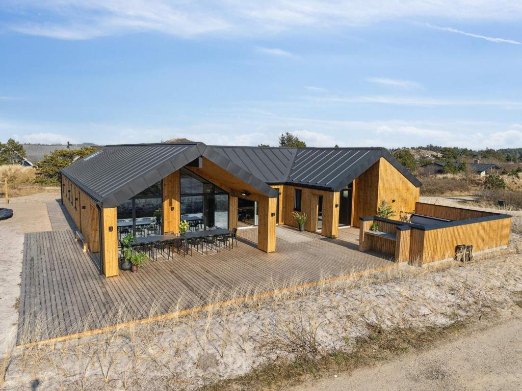 a house with a black roof on a wooden deck at 5 star holiday home in Henne Beach in Henne Strand