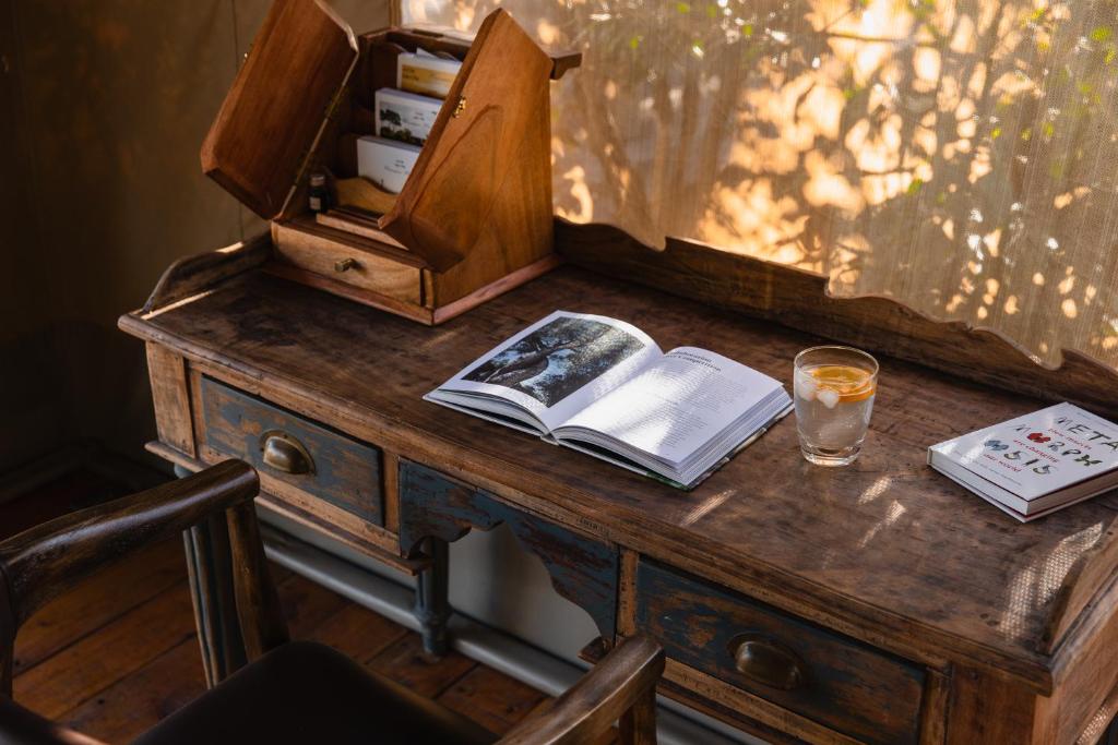 una scrivania in legno con un libro e un bicchiere di drink di Enkusero Mara ad Aitong