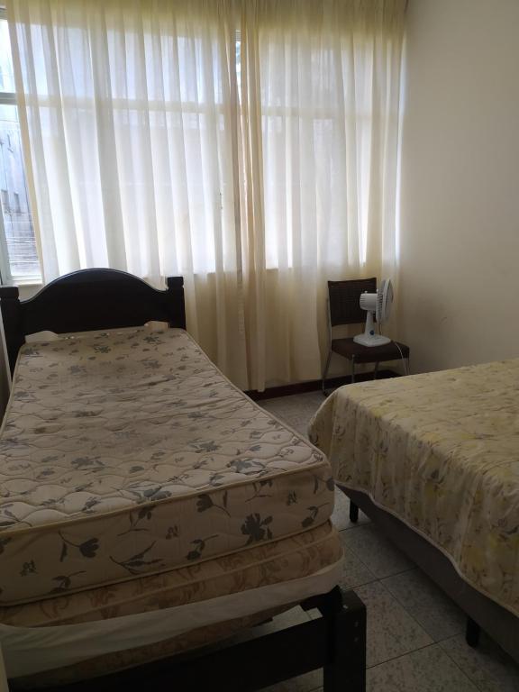 ein Schlafzimmer mit zwei Betten, einem Stuhl und einem Fenster in der Unterkunft Centro - Perto de tudo in Salvador