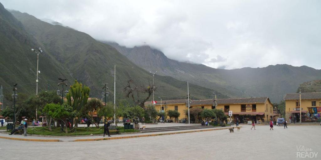 a group of people in a town with mountains in the background at plaza in Ollantaytambo