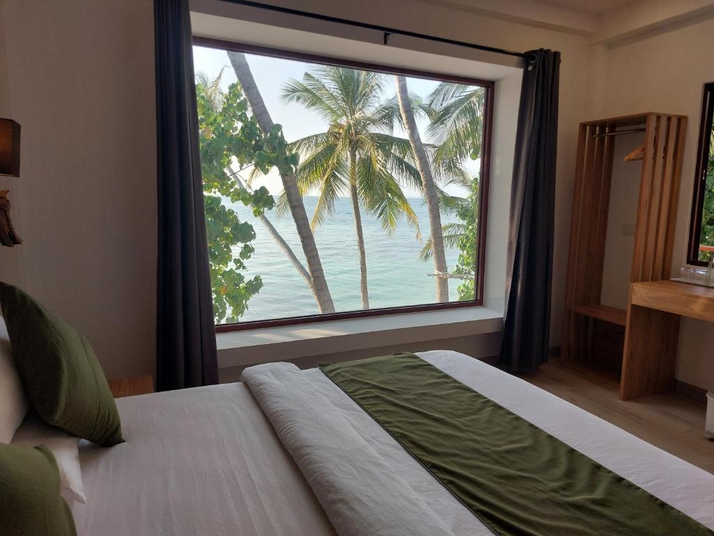 a bedroom with a large window with palm trees at Comfy Cool Breeze by eMzaz in Dhiffushi