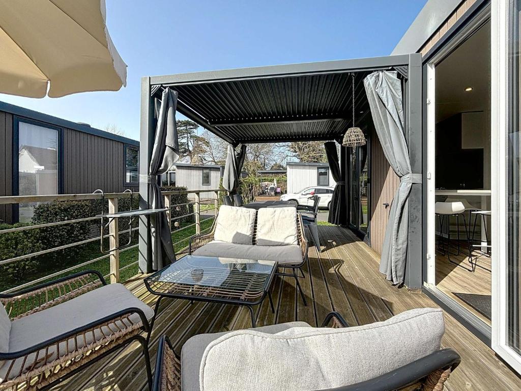 un patio avec des chaises et une table sur une terrasse dans l'établissement Mobil-home Grand Confort à Jullouville - Plage, Piscine Chauffée, Fitness et Parking - FR-1-361A-66, à Jullouville