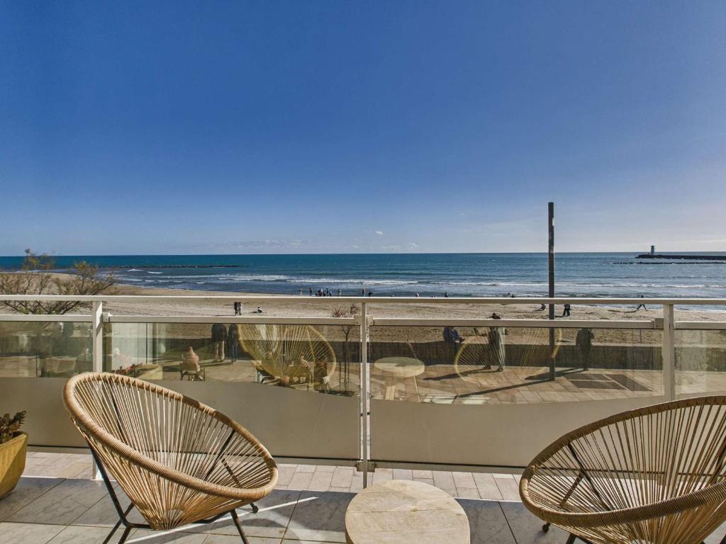 - un balcon avec 2 chaises et la plage dans l'établissement Maison 8 pers Front de Mer - Grau d'Agde - FR-1-423-320, au Grau-dʼAgde