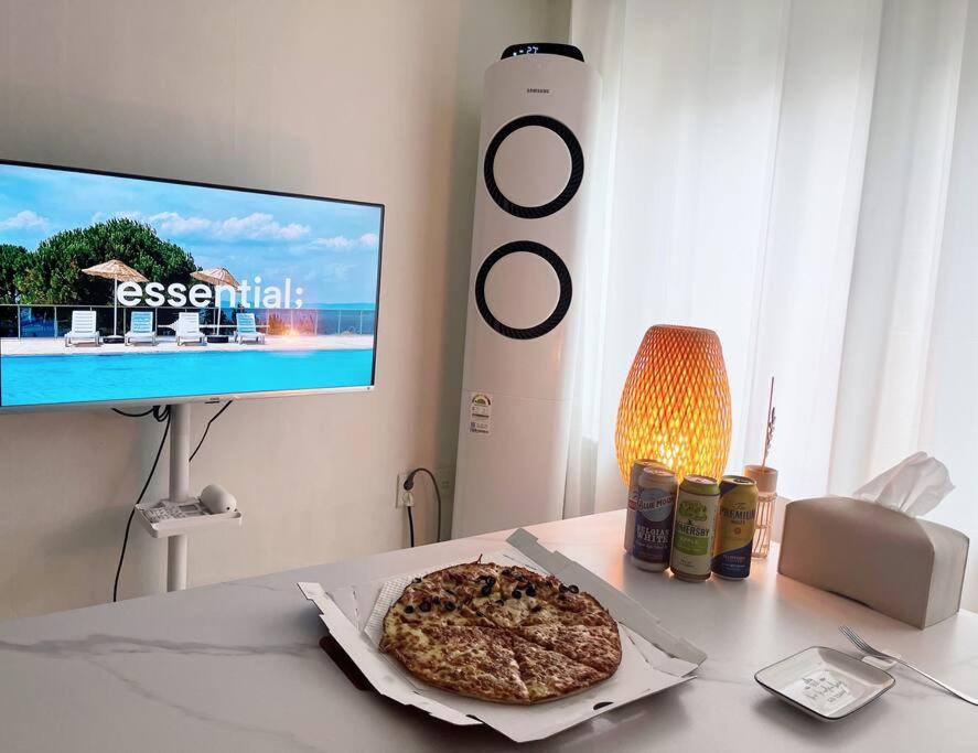 una pizza sentada en una mesa frente a una TV en Cozy 2BR Netflix Metro 5min Jamsil,Gangnam, en Seongnam