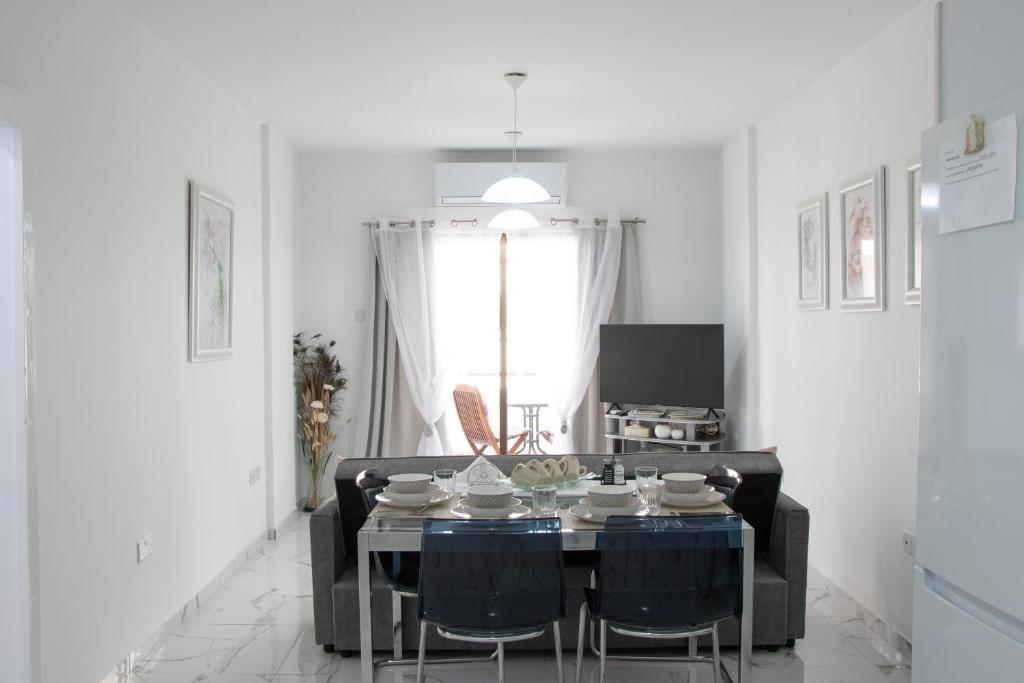 a white living room with a table and chairs at Apartment,NEAR THE BEACH Pinikoudes in Larnaka